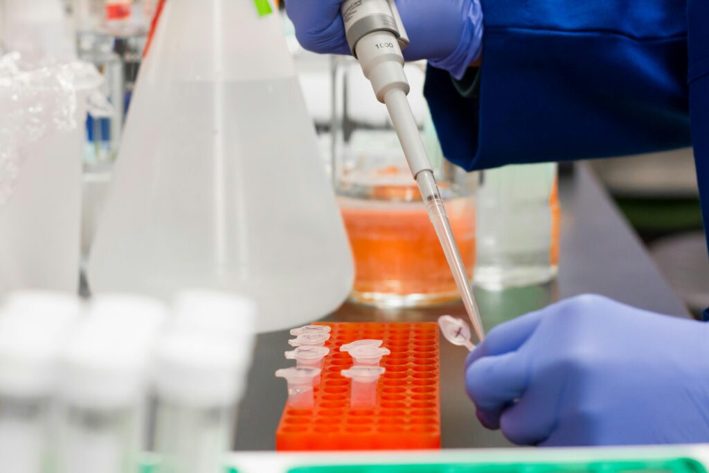 Close-up of a scientist using pipette in laboratory with test tubes.