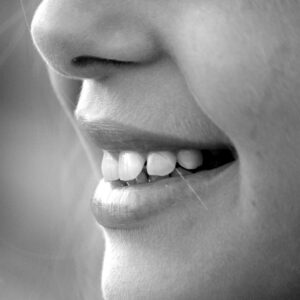 A monochrome close-up of a smiling face showcasing teeth and lips.